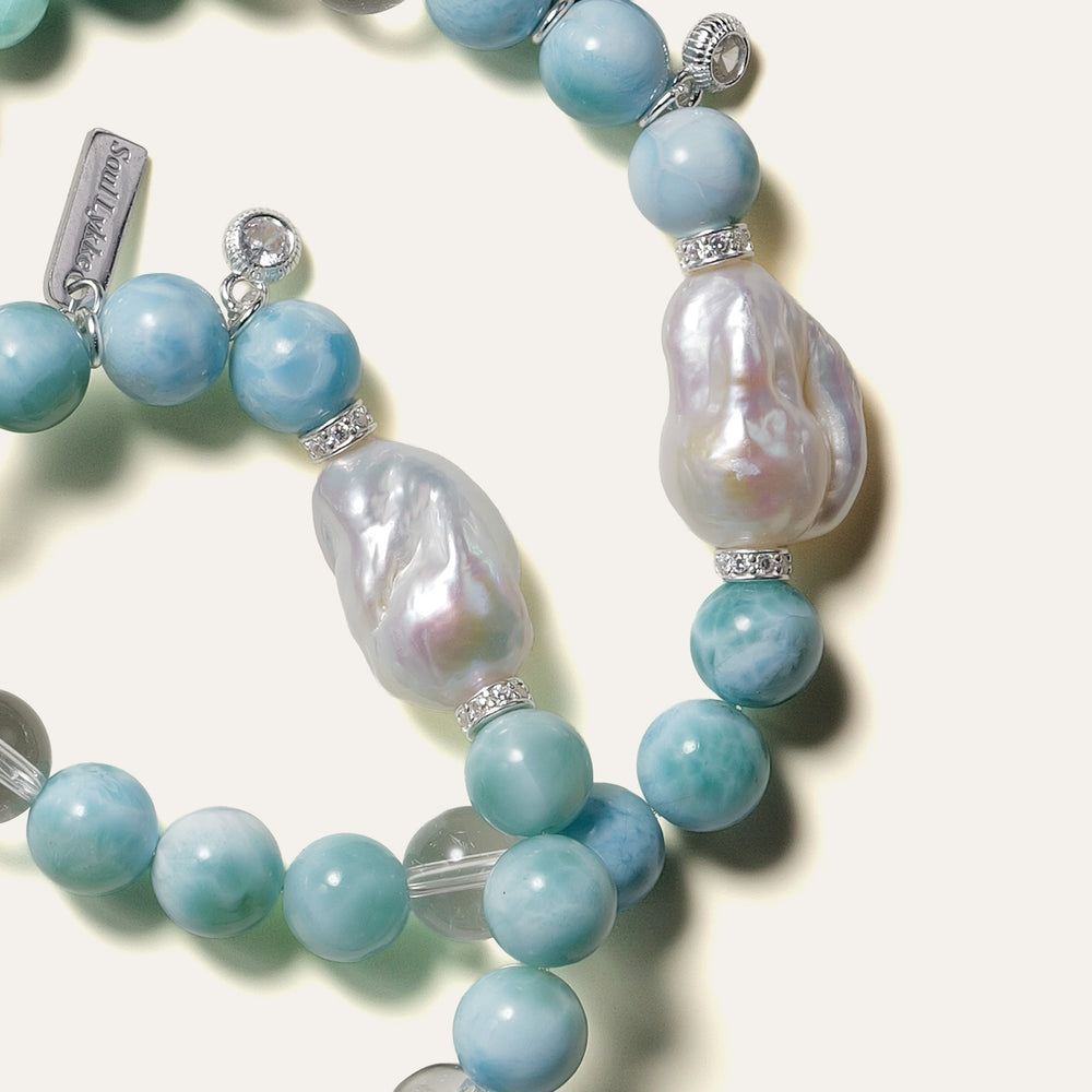The Marine Veil bracelet by Soul Lykke, featuring an authentic 20mm East Asian baroque pearl centerpiece, surrounded by 8mm AA grade Dominican Larimar, clear quartz, and 925 sterling silver CZ spacers on a neutral background. This is a natural gemstone and healing crystal bracelet by Soul Lykke.