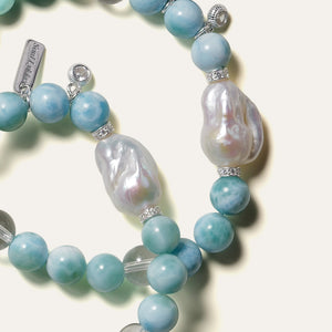 Extreme close-up of AA grade Dominican Larimar showcasing its unique wave-crest and tortoise-shell patterns, perfectly paired with the iridescent orient and mirror-like luster of a genuine organic baroque pearl.