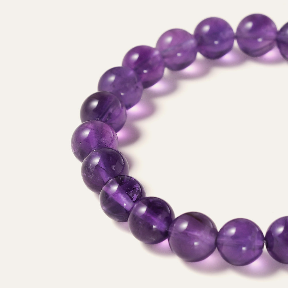 Core Essential bracelet featuring 8mm AA+ natural Brazilian Amethyst beads showcasing deep royal purple hues with the Soul Lykke 14K gold PVD signature bead. This is a natural gemstone and healing crystal bracelet by Soul Lykke.