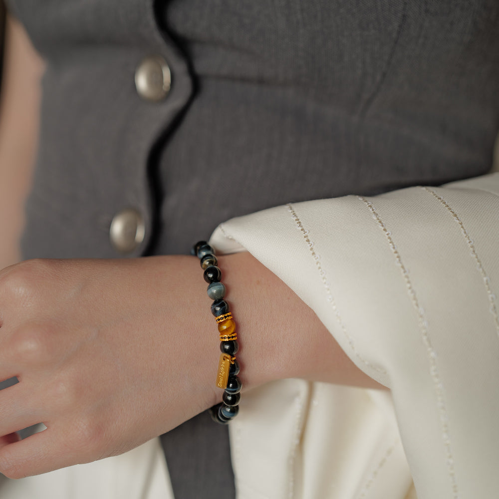 8mm natural Blue Tiger's Eye beaded bracelet featuring a golden Tiger's Eye center stone and a gold Soul Lykke tag. This is a natural gemstone and healing crystal bracelet by Soul Lykke.