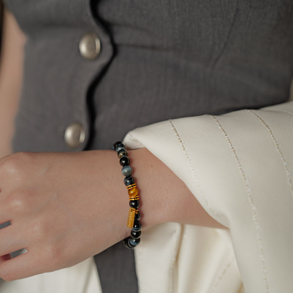 Close-up detail of the 6mm Blue Tiger's Eye bracelet, showcasing the gemstone's dense structure and vivid cat's eye chatoyancy. Accented by black CZ-encrusted gold spacers and a 14K gold PVD tag, this calming stone naturally soothes anxiety and clears mental fog.