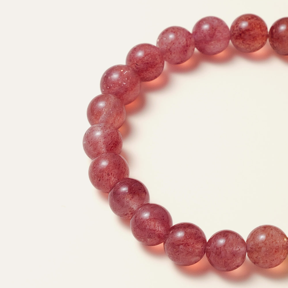 The Core Essential bracelet by Soul Lykke, featuring 8mm natural AAA star strawberry quartz from Madagascar and a solitary hypoallergenic 14K gold PVD surgical steel signature bead on a neutral background. This is a natural gemstone and healing crystal bracelet by Soul Lykke.