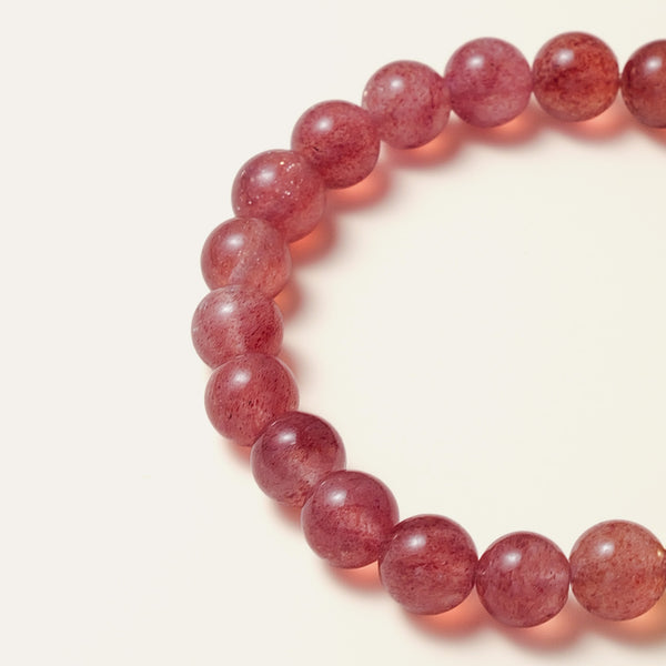 Macro detail of 8mm mid-berry pink star strawberry quartz, highlighting the gemstone's crystalline clarity and suspended natural hematite and mica flecks that reflect light like stardust.