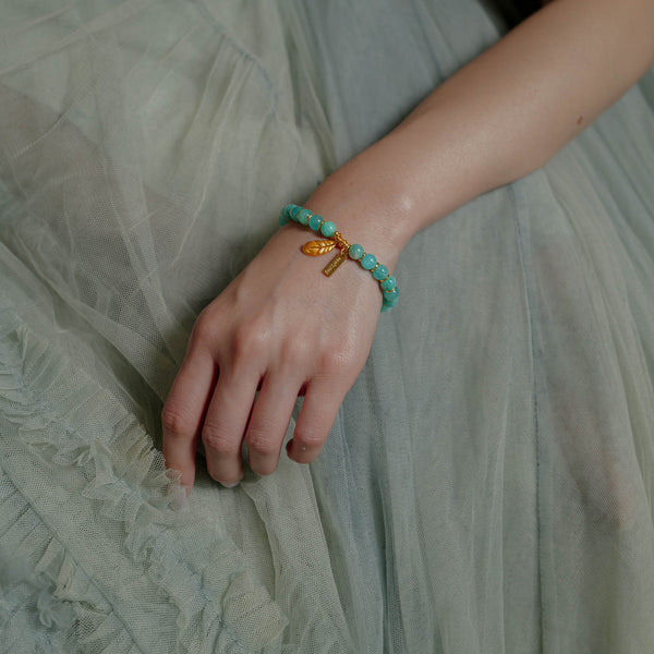 A woman wearing the dainty 7mm icy amazonite healing bracelet gracefully on her wrist. Revered as the Stone of Courage and Truth, this elegant crystal jewelry piece is designed to quiet mental noise and restore confidence.