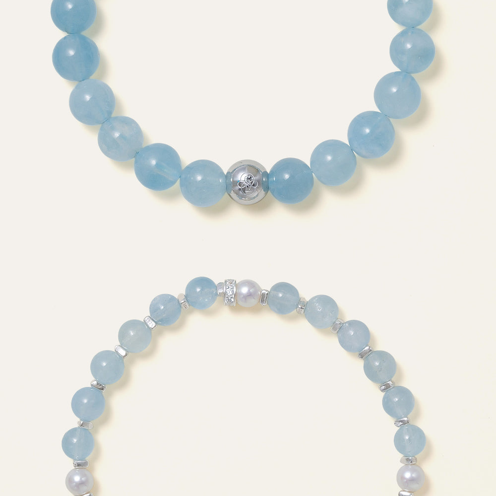 The Whispering Cove bracelet by Soul Lykke, featuring 6mm natural AAA Brazilian aquamarine and 5mm Japanese Akoya pearls with 925 sterling silver geometric spacers on a seamless background. This is a natural gemstone and healing crystal bracelet by Soul Lykke.
