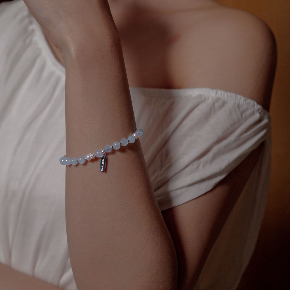 The Whispering Cove bracelet by Soul Lykke, featuring 6mm natural AAA Brazilian aquamarine and 5mm Japanese Akoya pearls with 925 sterling silver geometric spacers on a seamless background. This is a natural gemstone and healing crystal bracelet by Soul Lykke.