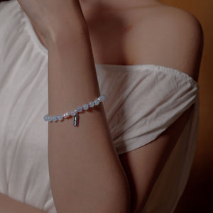 A woman elegantly wearing the 6mm natural aquamarine and Akoya pearl bracelet on her wrist. Revered for courage and serenity, this fine crystal jewelry provides soothing water energy to calm emotional tension.