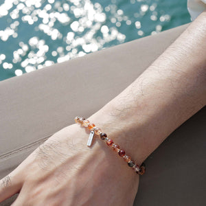 Close-up of a 6mm Black Gold Super Seven bracelet on a yacht, capturing the high-contrast shimmer of metallic black blades under natural light.