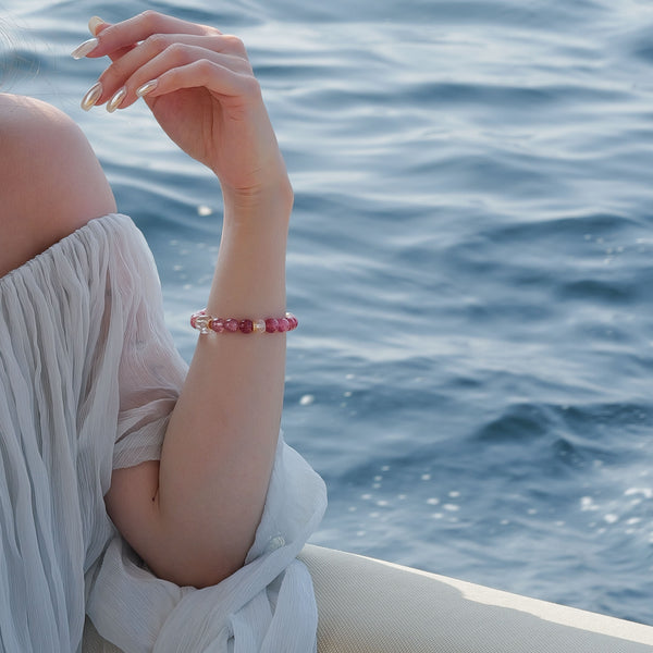 A high-jewelry styling of 8mm Lace Rhodochrosite and Star Strawberry Quartz on a yacht, radiating Heart Chakra synergy against a serene ocean.
