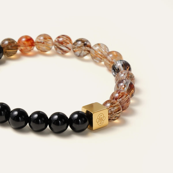 Close-up of golden-bronze rutiles in natural Black Gold Super Seven beads next to a glossy black Obsidian stone.