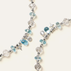Close-up of sparkling Blue Topaz teardrop, a cubic zirconia star, and 925 sterling silver charms on a faceted crystal bracelet.