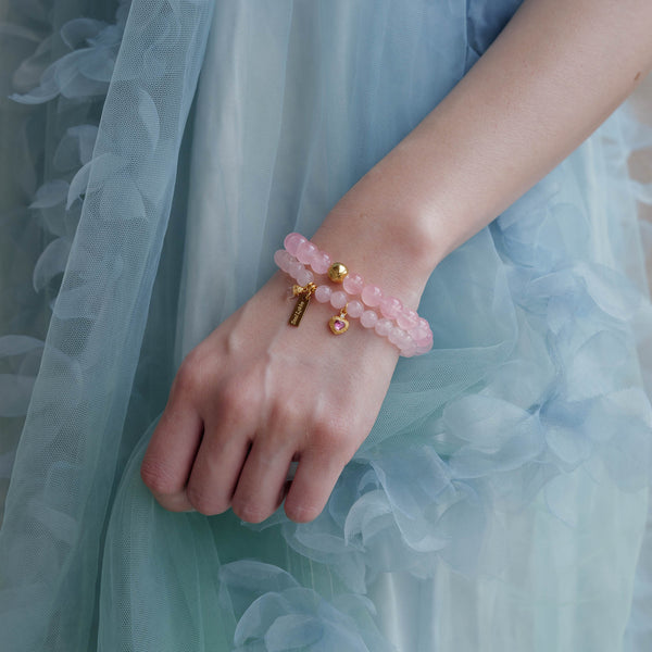 Model wearing stacked 8mm Hibiscus and 6mm Sakura pink Rose Quartz bracelets, featuring jelly translucency and a vintage Pink Tourmaline charm.