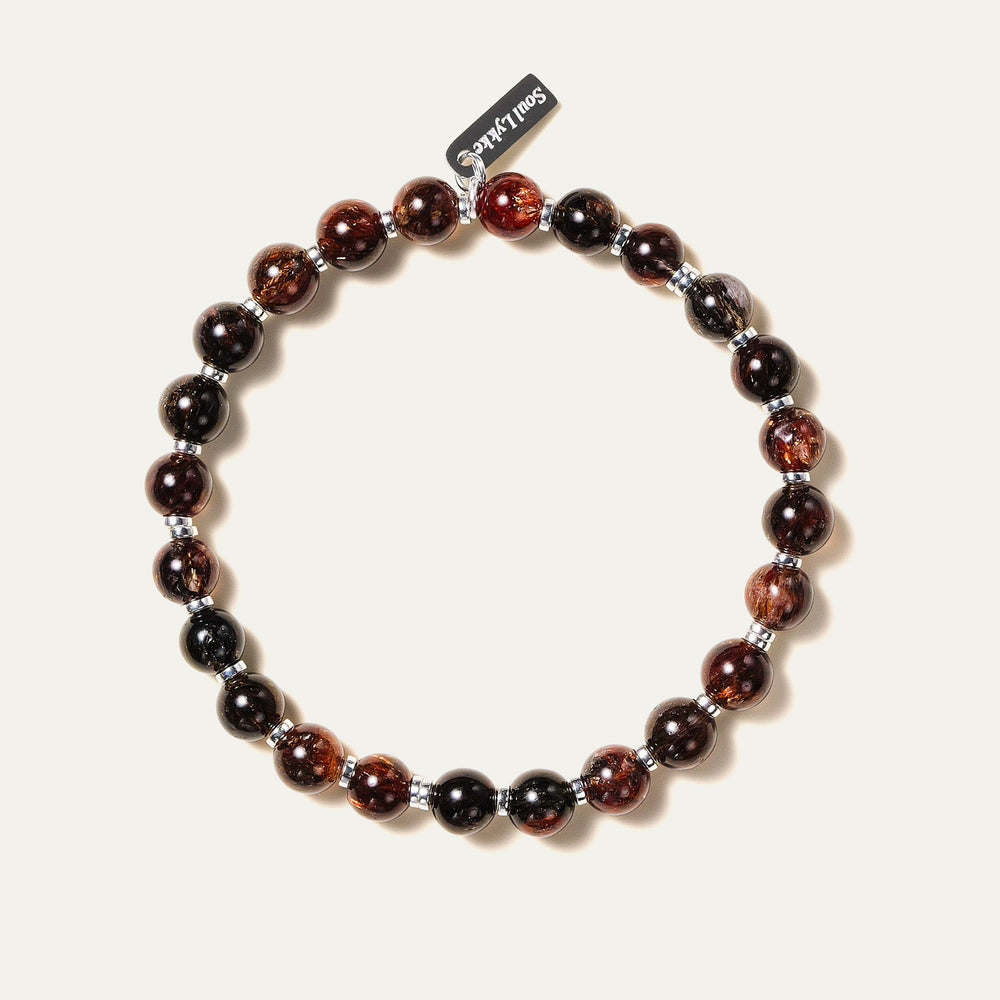 The Eclipse Gold bracelet by Soul Lykke in natural light. Featuring collector-grade 6mm AAA Black Gold Super Seven and high-polished 925 sterling silver spacers, this piece commands an enigmatic, near-solid black presence for understated luxury. This is a natural gemstone and healing crystal bracelet by Soul Lykke.