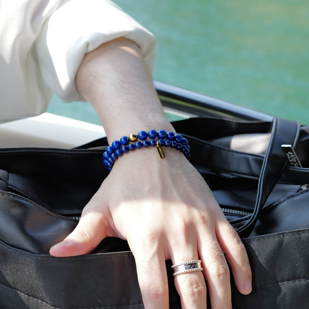 The Royal Vesper bracelet by Soul Lykke, featuring 6mm AAA-grade natural Afghan Lapis Lazuli. This luxury crystal jewelry showcases deep royal blue stones with golden pyrite flakes and an intricate pavé CZ gold barrel bead. This is a natural gemstone bracelet by Soul Lykke.