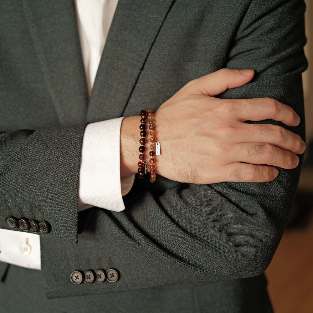 The Eclipse Gold bracelet by Soul Lykke in natural light. Featuring collector-grade 6mm AAA Black Gold Super Seven and high-polished 925 sterling silver spacers, this piece commands an enigmatic, near-solid black presence for understated luxury. This is a natural gemstone and healing crystal bracelet by Soul Lykke.