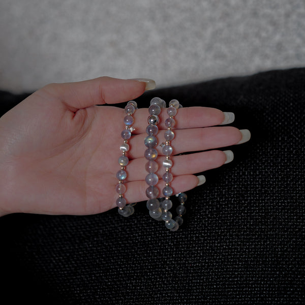 Close-up detail of authentic Labradorite beads displaying luminous blue flashes (labradorescence) with premium 925 sterling silver spacer accents, held gently in a hand.