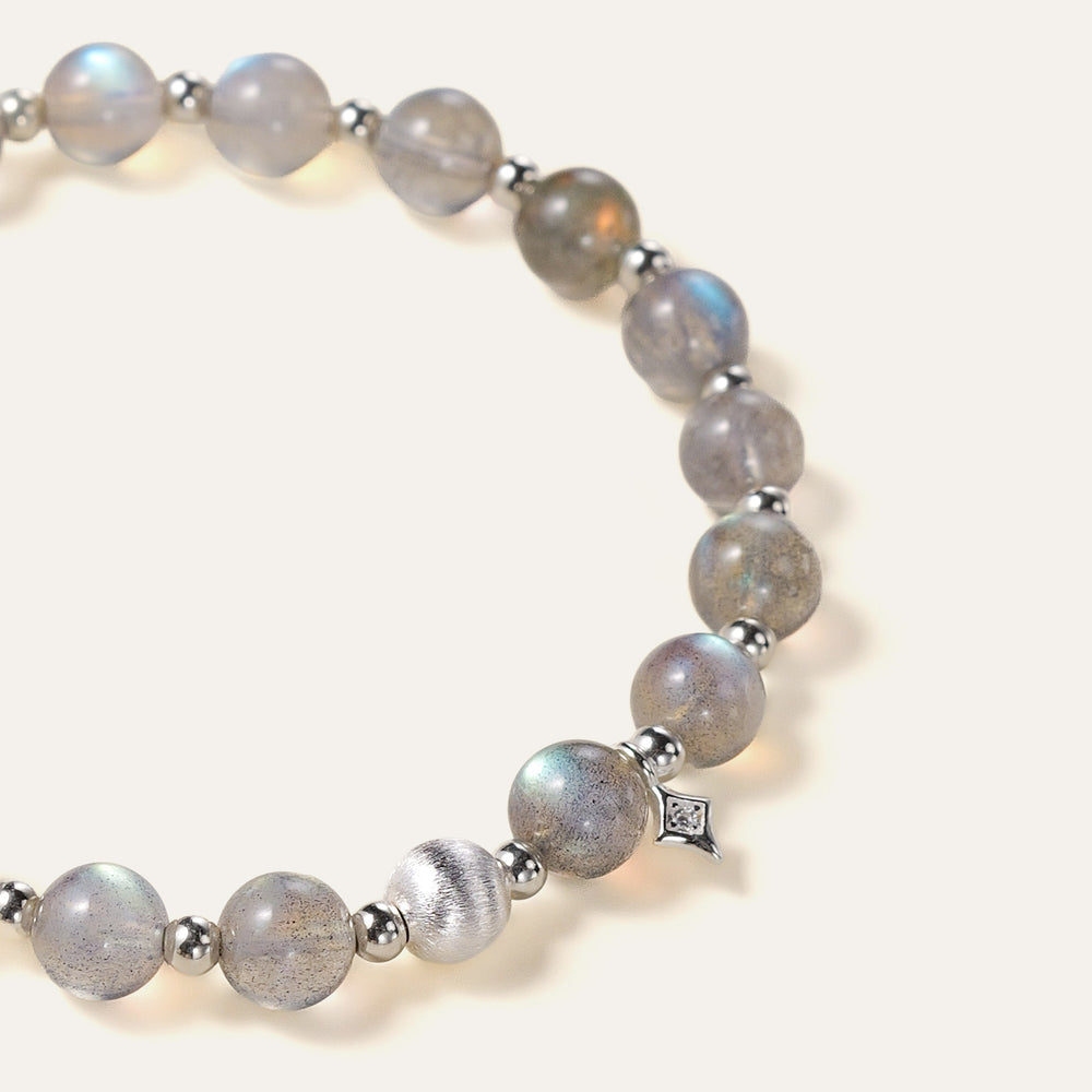 Top-down view of the Soul Lykke Inner Universe bracelet, featuring 6.5-7mm natural AAA-grade Madagascar Labradorite with vivid spectral flashes, accented by 925 sterling silver hardware and a white gold PVD surgical steel tag. This is a natural gemstone and healing crystal bracelet by Soul Lykke.