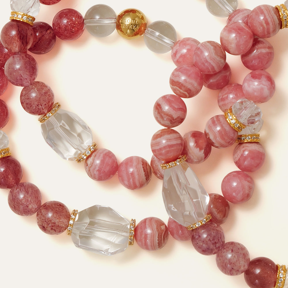 Elegant beaded bracelet combining 8mm natural Lace Rhodochrosite, Star Strawberry Quartz, and a faceted Clear Quartz centerpiece, featuring the Soul Lykke signature gold bead. This is a natural gemstone and healing crystal bracelet by Soul Lykke.