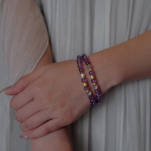 Two handcrafted natural gemstone bracelets layered on a woman's wrist, showcasing deep violet Amethyst hues contrasted with subtle silvery-blue Labradorite flashes in a demi-fine jewelry style.