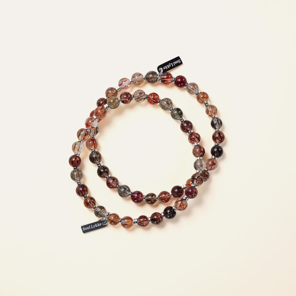 Two handcrafted Soul Lykke Black Gold Super Seven bracelets layered together, showcasing striking metallic blades and golden rutiles.