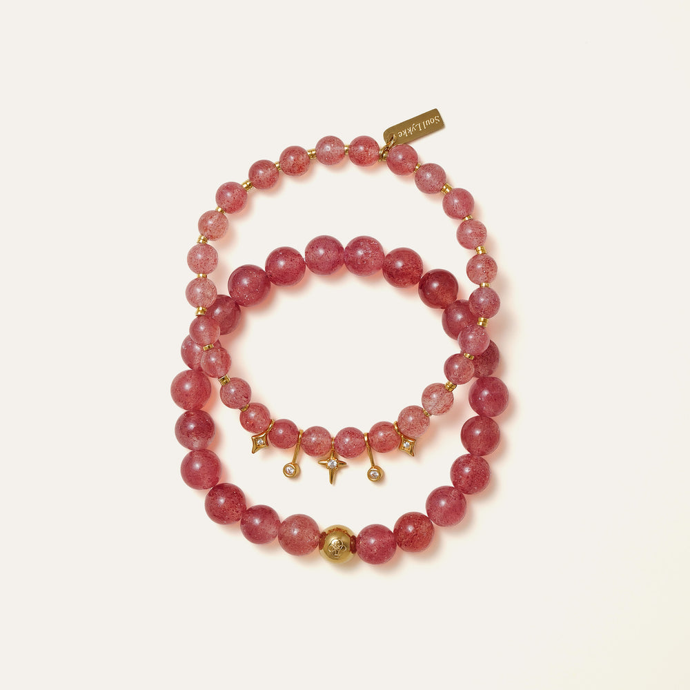 The Core Essential bracelet by Soul Lykke, featuring 8mm natural AAA star strawberry quartz from Madagascar and a solitary hypoallergenic 14K gold PVD surgical steel signature bead on a neutral background. This is a natural gemstone and healing crystal bracelet by Soul Lykke.