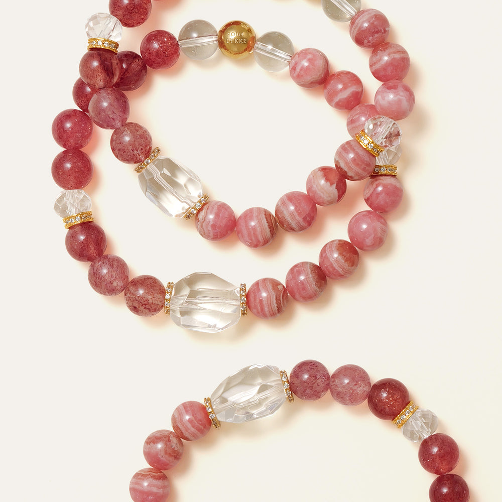 Elegant beaded bracelet combining 8mm natural Lace Rhodochrosite, Star Strawberry Quartz, and a faceted Clear Quartz centerpiece, featuring the Soul Lykke signature gold bead. This is a natural gemstone and healing crystal bracelet by Soul Lykke.