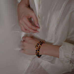 A beautifully layered stack of 6mm and 8mm AAA Tiger's Eye bracelets worn gracefully on a wrist. This powerful crystal combination acts as a magnetic draw for abundance and quiet authority.