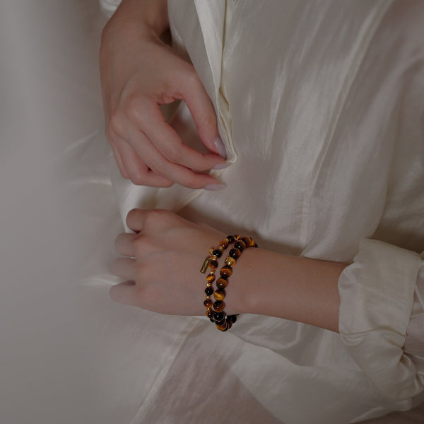 A beautifully layered stack of 6mm and 8mm AAA Tiger's Eye bracelets worn gracefully on a wrist. This powerful crystal combination acts as a magnetic draw for abundance and quiet authority.