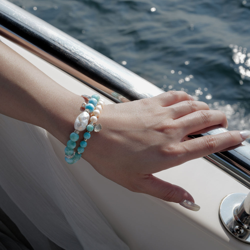 Top view of The Marine Tear artisan bracelet by Soul Lykke, featuring a half-and-half design of 6mm AA grade Dominican Larimar and natural freshwater pearls with a silver seashell charm. This is a natural gemstone and healing crystal bracelet by Soul Lykke.