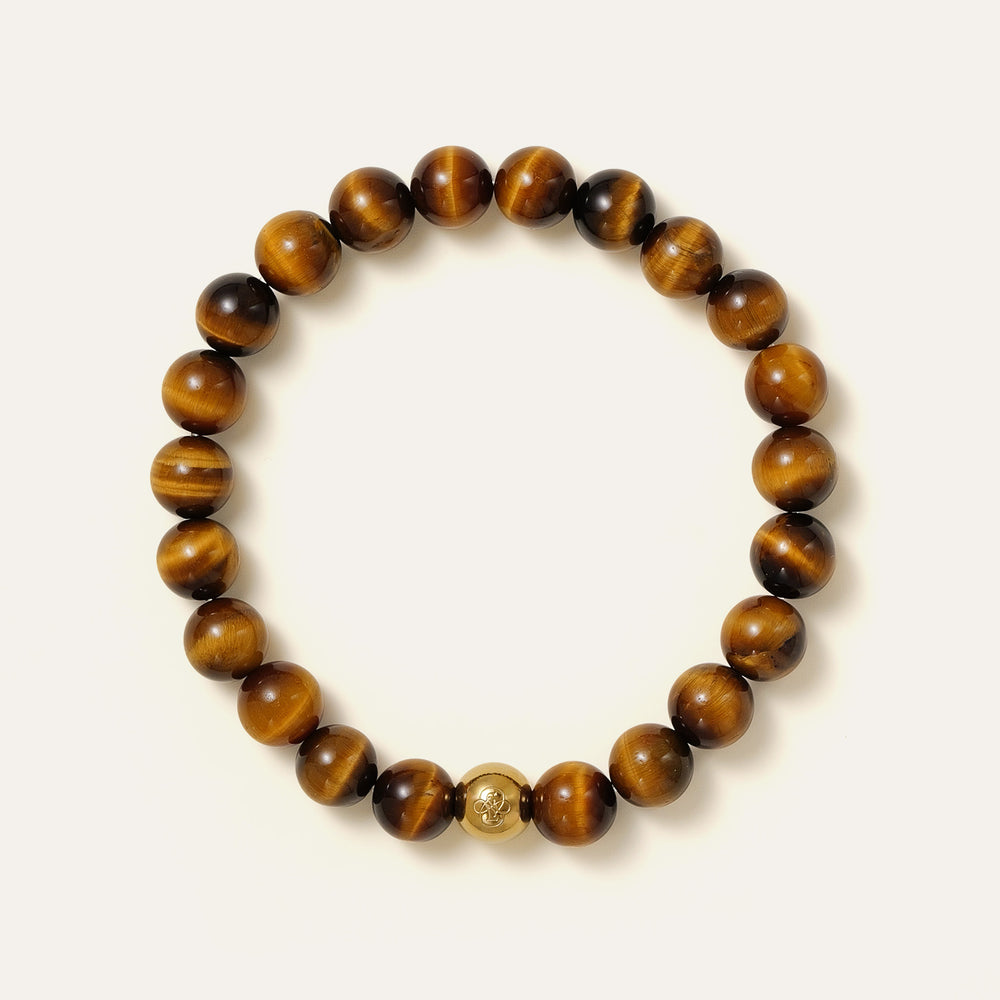 The Core Essential bracelet by Soul Lykke, featuring ethically sourced 8mm natural AAA Tiger's Eye beads from South Africa and a single engraved 14K gold PVD surgical steel signature bead on a seamless neutral background. This is a natural gemstone and healing crystal bracelet by Soul Lykke.