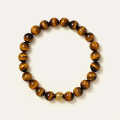 The Core Essential bracelet by Soul Lykke, featuring ethically sourced 8mm natural AAA Tiger's Eye beads from South Africa and a single engraved 14K gold PVD surgical steel signature bead on a seamless neutral background. This is a natural gemstone and healing crystal bracelet by Soul Lykke.