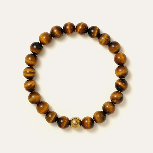 The Core Essential bracelet by Soul Lykke, featuring ethically sourced 8mm natural AAA Tiger's Eye beads from South Africa and a single engraved 14K gold PVD surgical steel signature bead on a seamless neutral background. This is a natural gemstone and healing crystal bracelet by Soul Lykke.