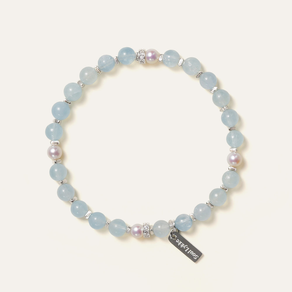 The Whispering Cove bracelet by Soul Lykke, featuring 6mm natural AAA Brazilian aquamarine and 5mm Japanese Akoya pearls with 925 sterling silver geometric spacers on a seamless background. This is a natural gemstone and healing crystal bracelet by Soul Lykke.