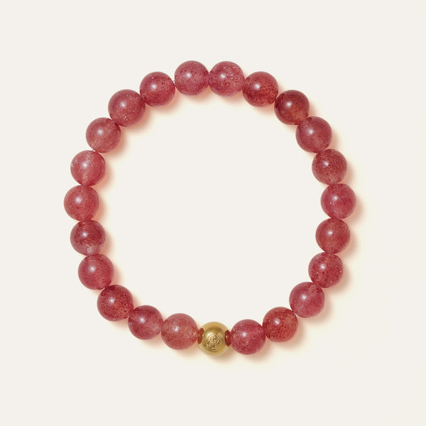 The Core Essential bracelet by Soul Lykke, featuring 8mm natural AAA star strawberry quartz from Madagascar and a solitary hypoallergenic 14K gold PVD surgical steel signature bead on a neutral background. This is a natural gemstone and healing crystal bracelet by Soul Lykke.