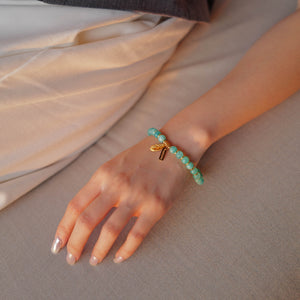 A woman elegantly styling the Tide & Feather natural Mozambique amazonite bracelet. Bathed in soft light, the vivid blue-green gemstones quiet mental noise and restore unshakeable confidence.