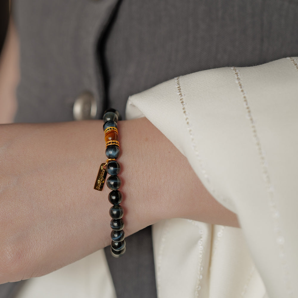 8mm natural Blue Tiger's Eye beaded bracelet featuring a golden Tiger's Eye center stone and a gold Soul Lykke tag. This is a natural gemstone and healing crystal bracelet by Soul Lykke.