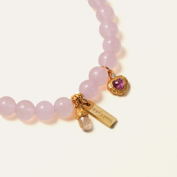 Close-up of the Soul Lykke Soft Bloom bracelet, detailing the 24K gold-plated filigree heart set with genuine Pink Tourmaline and a Rose Quartz drop.