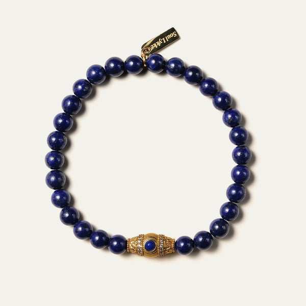 The Royal Vesper bracelet by Soul Lykke, featuring 6mm AAA-grade natural Afghan Lapis Lazuli. This luxury crystal jewelry showcases deep royal blue stones with golden pyrite flakes and an intricate pavé CZ gold barrel bead. This is a natural gemstone bracelet by Soul Lykke.