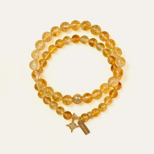 Two stacked premium natural Honey Citrine bracelets, one with an engraved Soul Lykke brand tag and 14K gold star charm with clear crystals, designed for conscious manifestors seeking abundance and success.