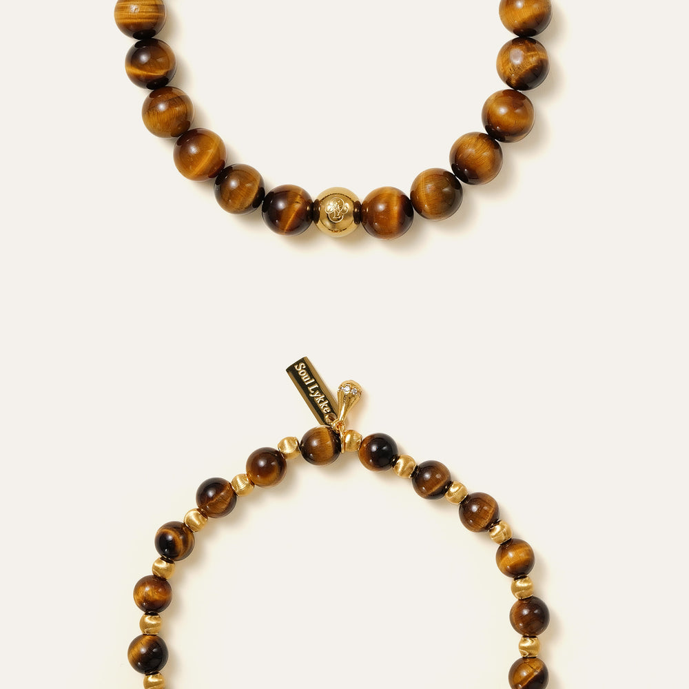 The Core Essential bracelet by Soul Lykke, featuring ethically sourced 8mm natural AAA Tiger's Eye beads from South Africa and a single engraved 14K gold PVD surgical steel signature bead on a seamless neutral background. This is a natural gemstone and healing crystal bracelet by Soul Lykke.
