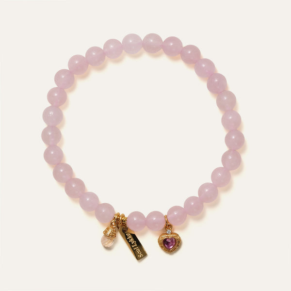 Soft Bloom bracelet by Soul Lykke featuring 6mm AAA Sakura Pink Rose Quartz, a pink tourmaline filigree heart, and a 14K gold PVD signature tag. This is a natural gemstone and healing crystal bracelet by Soul Lykke.