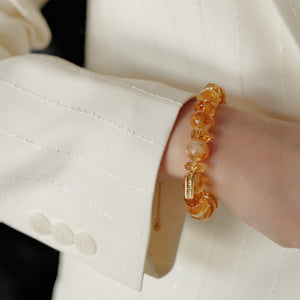 Model in a white blazer wearing the Soul Lykke 12mm Golden Phantom Citrine bracelet, featuring alternating faceted beads and a 14K gold tag.