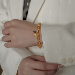 Close-up of a woman's wrist wearing a handcrafted 6mm AAA Brazil Citrine bracelet against a white suit jacket, blending effortless elegance with the energetic abundance properties of the stone.
