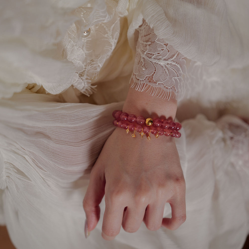 The Core Essential bracelet by Soul Lykke, featuring 8mm natural AAA star strawberry quartz from Madagascar and a solitary hypoallergenic 14K gold PVD surgical steel signature bead on a neutral background. This is a natural gemstone and healing crystal bracelet by Soul Lykke.