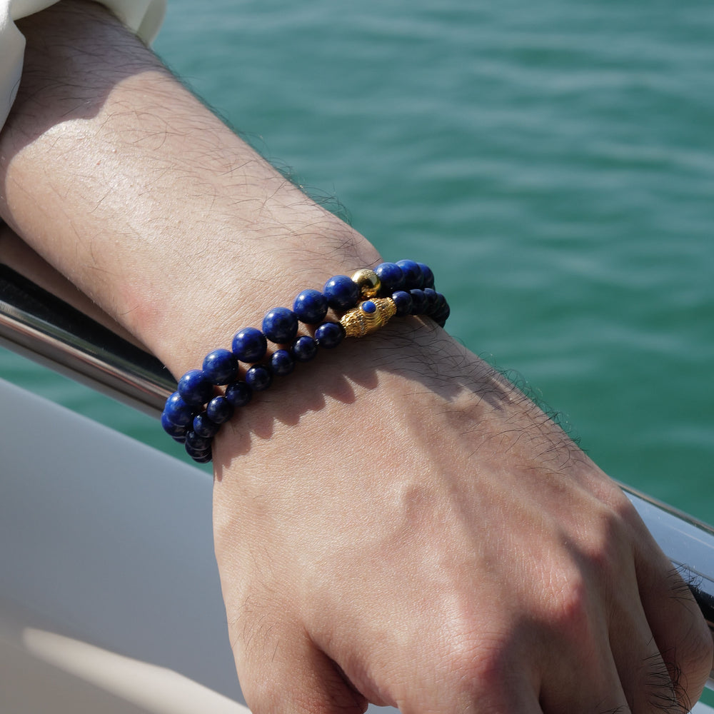 The Royal Vesper bracelet by Soul Lykke, featuring 6mm AAA-grade natural Afghan Lapis Lazuli. This luxury crystal jewelry showcases deep royal blue stones with golden pyrite flakes and an intricate pavé CZ gold barrel bead. This is a natural gemstone bracelet by Soul Lykke.