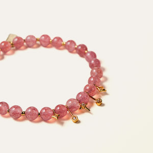 Close-up of delicate 6mm natural Star Strawberry Quartz beads revealing shimmering red mineral flecks and gold-plated sterling silver charms.
