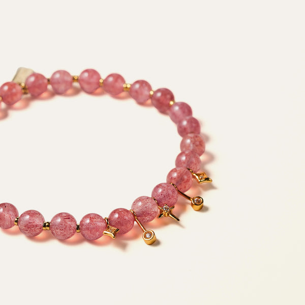 Close-up of delicate 6mm natural Star Strawberry Quartz beads revealing shimmering red mineral flecks and gold-plated sterling silver charms.