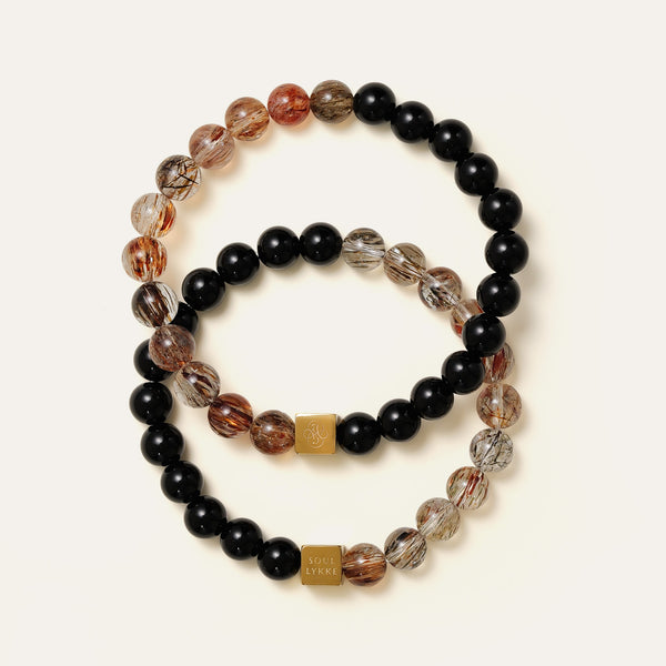 Two Black Gold Super Seven and Obsidian split bracelets stacked together, showcasing varying natural rutile patterns.

圖 5 (疊搭特寫圖).