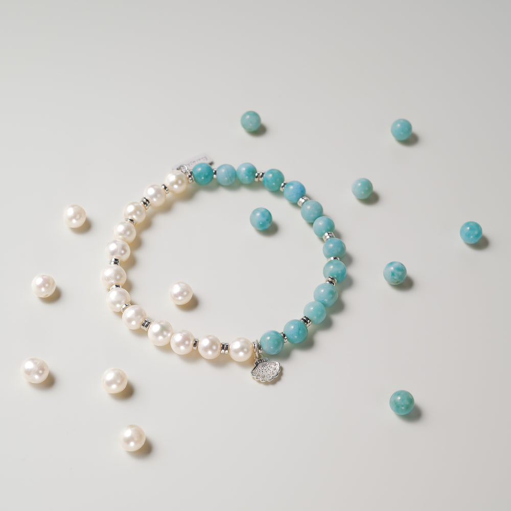 Top view of The Marine Tear artisan bracelet by Soul Lykke, featuring a half-and-half design of 6mm AA grade Dominican Larimar and natural freshwater pearls with a silver seashell charm. This is a natural gemstone and healing crystal bracelet by Soul Lykke.
