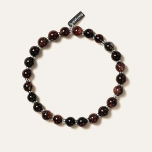 The Eclipse Gold bracelet by Soul Lykke in natural light. Featuring collector-grade 6mm AAA Black Gold Super Seven and high-polished 925 sterling silver spacers, this piece commands an enigmatic, near-solid black presence for understated luxury. This is a natural gemstone and healing crystal bracelet by Soul Lykke.